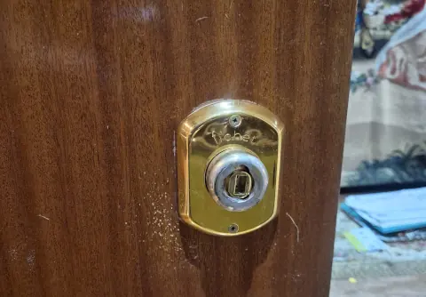 Cerrojo de seguridad Fichet dorado en una puerta de madera